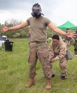 A New York National Guard Soldier with the 222nd Chemical Company, 104th Military Police Battalion performs a decontamination exercise at Fort Indiantown Gap on May 14. Another solider carefully removes the gas mask for gear decontaminating.