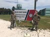 Kentucky National Guard Staff Sgt. Brian Bingham and Maj. Stephen Young pose beside the sign for the Belize Coast Guard (BCG) Forward Operating Base in Calabash Caye, Belize on May 6, 2022. Bingham and Young worked with the BCG to establish communications between all the different training sites involved in SOUTHCOM-sponsored Operations Tradewinds 2022 (U.S. Army photo courtesy of Maj. Stephen Young).