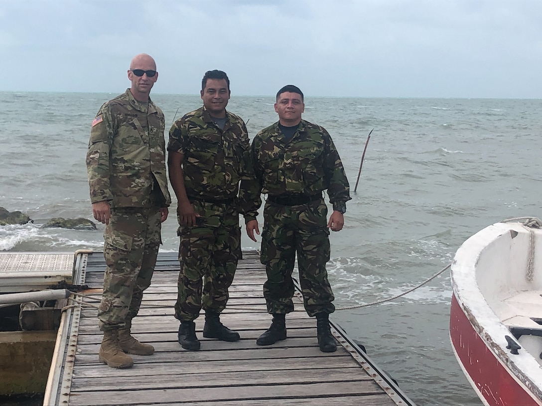 Kentucky National Guard Staff Sgt. Brian Bingham and two Belize Defence Forces (BDF) pose on dock in Calabash Caye, Belize on May 6, 2022. Bingham worked with the BDF to establish communications between all the different training sites involved in SOUTHCOM-sponsored Operations Tradewinds 2022 (U.S. Army photo courtesy of Maj. Stephen Young).