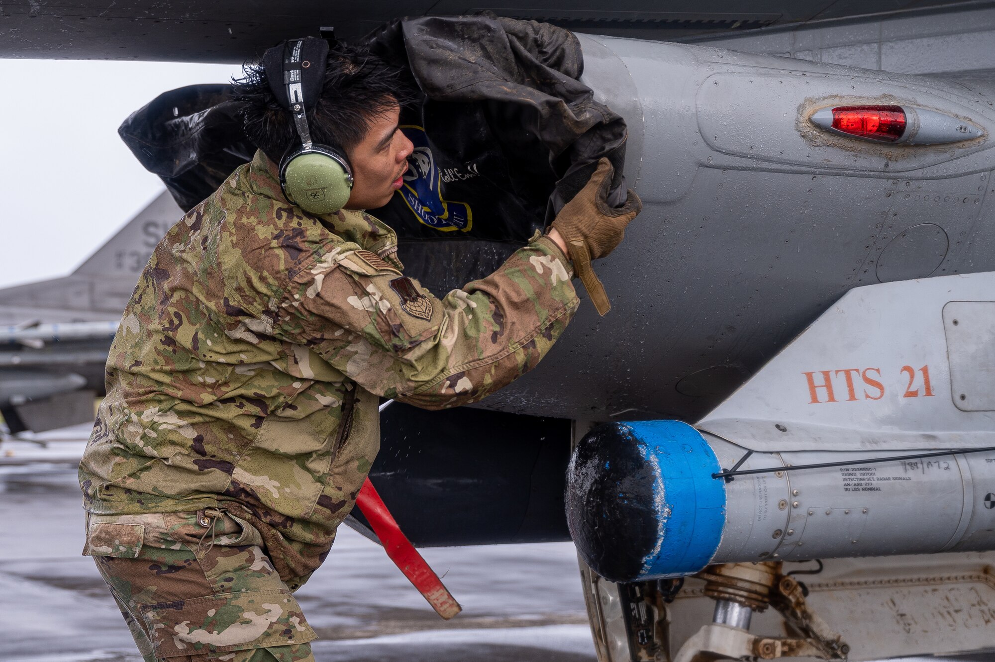 An Airman secures an intake cover during the recovery of an F-16 aircraft.