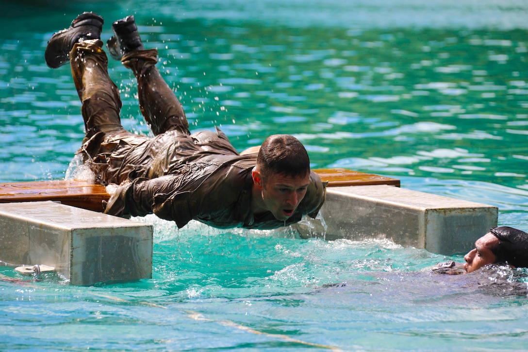 A soldier moves over a board above a water’s surface.