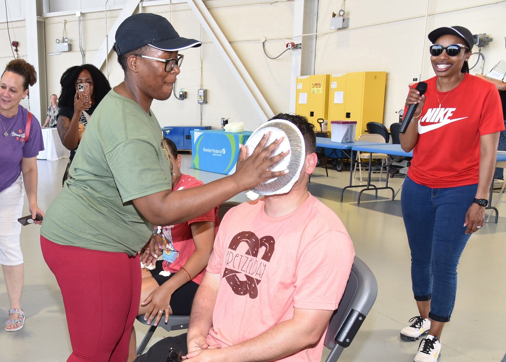 Sergeant Goosby holds a pie to the face of sergeant Rodriguez as onlookers watch