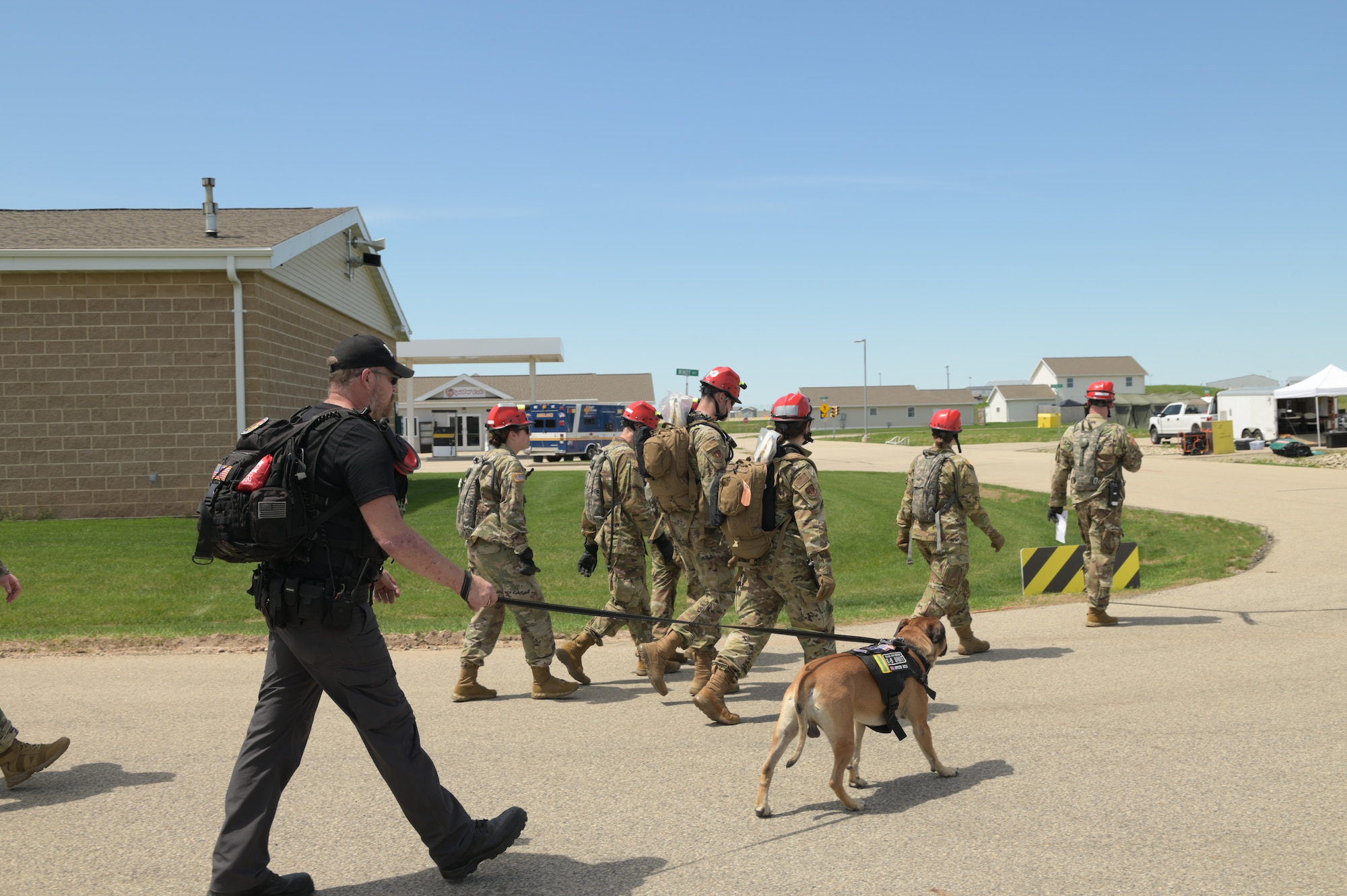 A group of soldiers and members from civilian agencies walk towards a building.