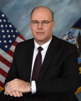 photo of Paul A. Pollock, posing in front of flags