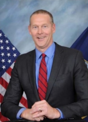 photo of Andrew Saunders posing in front of flags