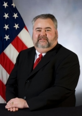 Scott Forrest, Assistant posing in front of the United States flag