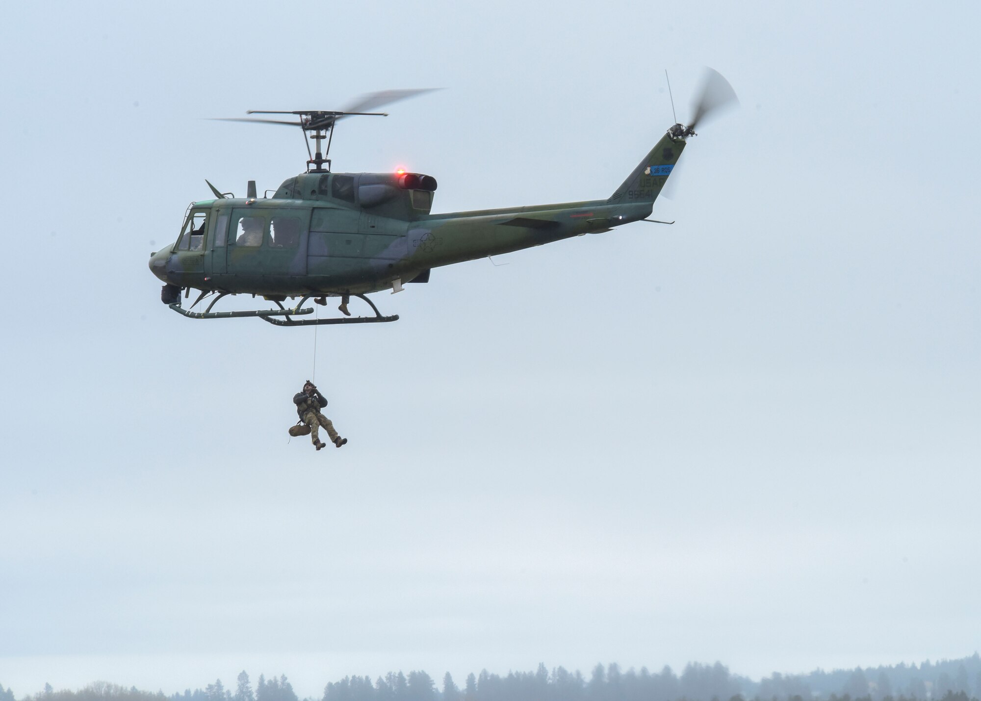 A U.S. Air Force Survival Evasion Resistance Escape Airman is hoisted up into a UH-1 Huey helicopter for a SERE demonstration during Skyfest 2022 at Fairchild Air Force Base, Washington, May 14, 2022. Fairchild Skyfest 2022 offered a unique view of Team Fairchild's role in enabling Rapid Global Mobility for the U.S. Air Force. (U.S. Air Force photo by Senior Airman Anneliese Kaiser)