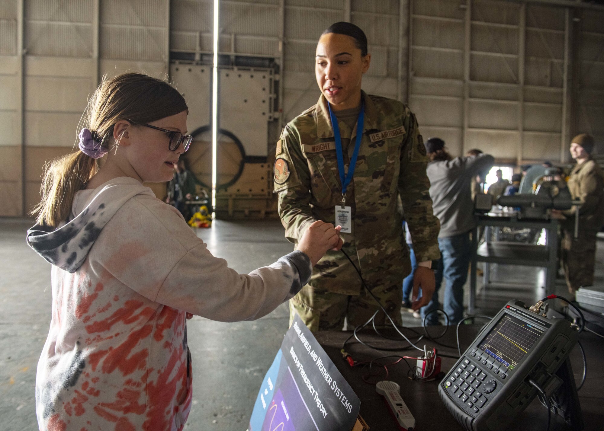 A U.S. Air Force Airman showcases communication equipment to an airshow visitor during the Fairchild Skyfest 2022 at Fairchild Air Force Base, Washington, May 15, 2022. Fairchild Skyfest 2022 offered a unique view of Team Fairchild's role in enabling Rapid Global Mobility for the U.S. Air Force. (U.S. Air Force photo by Staff Sgt. Lawrence Sena)