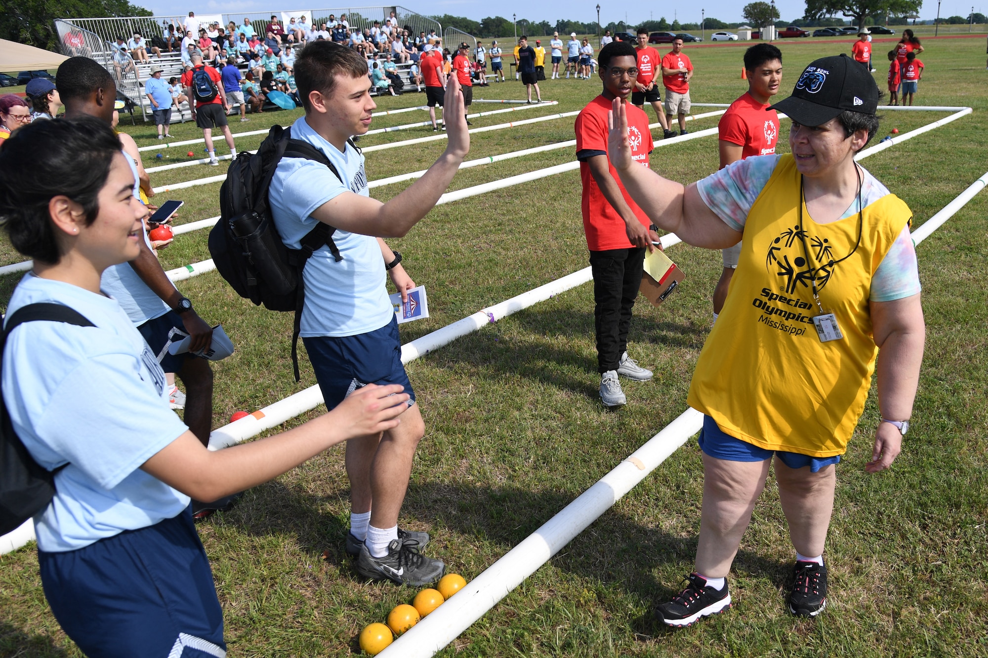 U.S. Air Force Airman Rachel Chi and Airman Basic Parker Ogle, 336th Training Squadron students, high-five Teresa Luna, Area 1 athlete, during the Special Olympics Mississippi Summer Games at Keesler Air Force Base, Miss., May 14, 2022. Over 600 athletes participated in the Summer Games. (U.S. Air Force photo by Kemberly Groue)