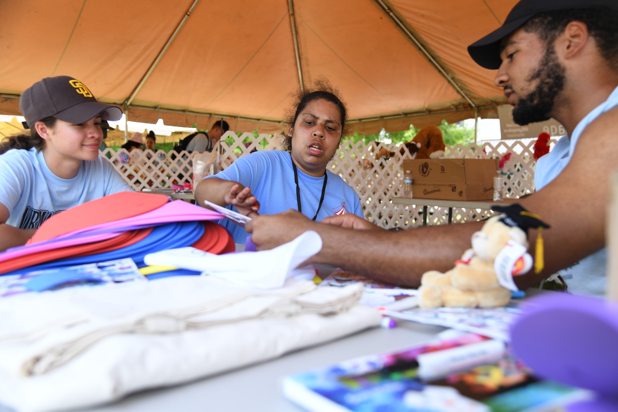 U.S. Air Force Airmen Alisiah Velasquez and Lazaro Valdes, 336th Training Squadron students, assist Tracey Smith, Area 3 athlete, with decorating a sun visor, during the Special Olympics Mississippi Summer Games at Keesler Air Force Base, Miss., May 14, 2022. Over 600 athletes participated in the Summer Games. (U.S. Air Force photo by Kemberly Groue)