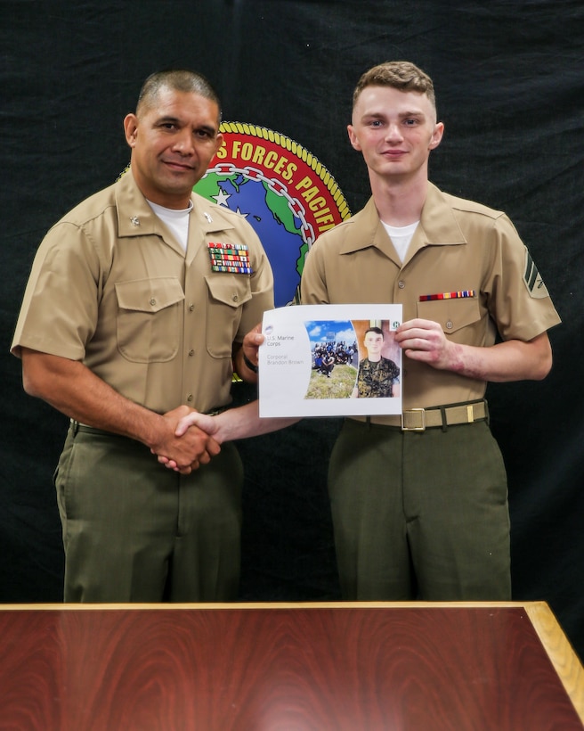 U.S. Marine Corps Cpl. Brandon A. Brown (right), and administrative specialist with Headquarters and Service Battalion (HQSVCBN), U.S. Marine Corps Forces, Pacific (MARFORPAC), shakes hands with Col. Eduardo A. Bitanga II, Commander, HQSVCBN, MARFORPAC during a Chamber of Commerce of Hawaii sponsored virtual Military Appreciation Month Ceremony Camp H. M. Smith, Hawaii on May 6. Members of each service were selected by their commands to be recognized during the ceremony for their outstanding community service. 
(U.S. Marine Corps photo by Cpl. Maximilian C. Campbell)