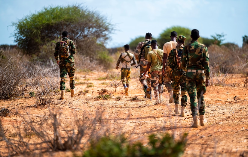 Men in military uniforms walk together outdoors.