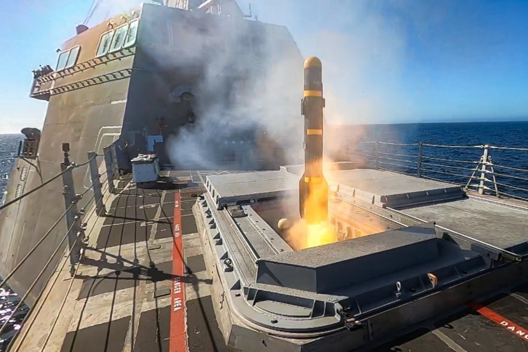 A missile launches from the deck of a ship at sea.