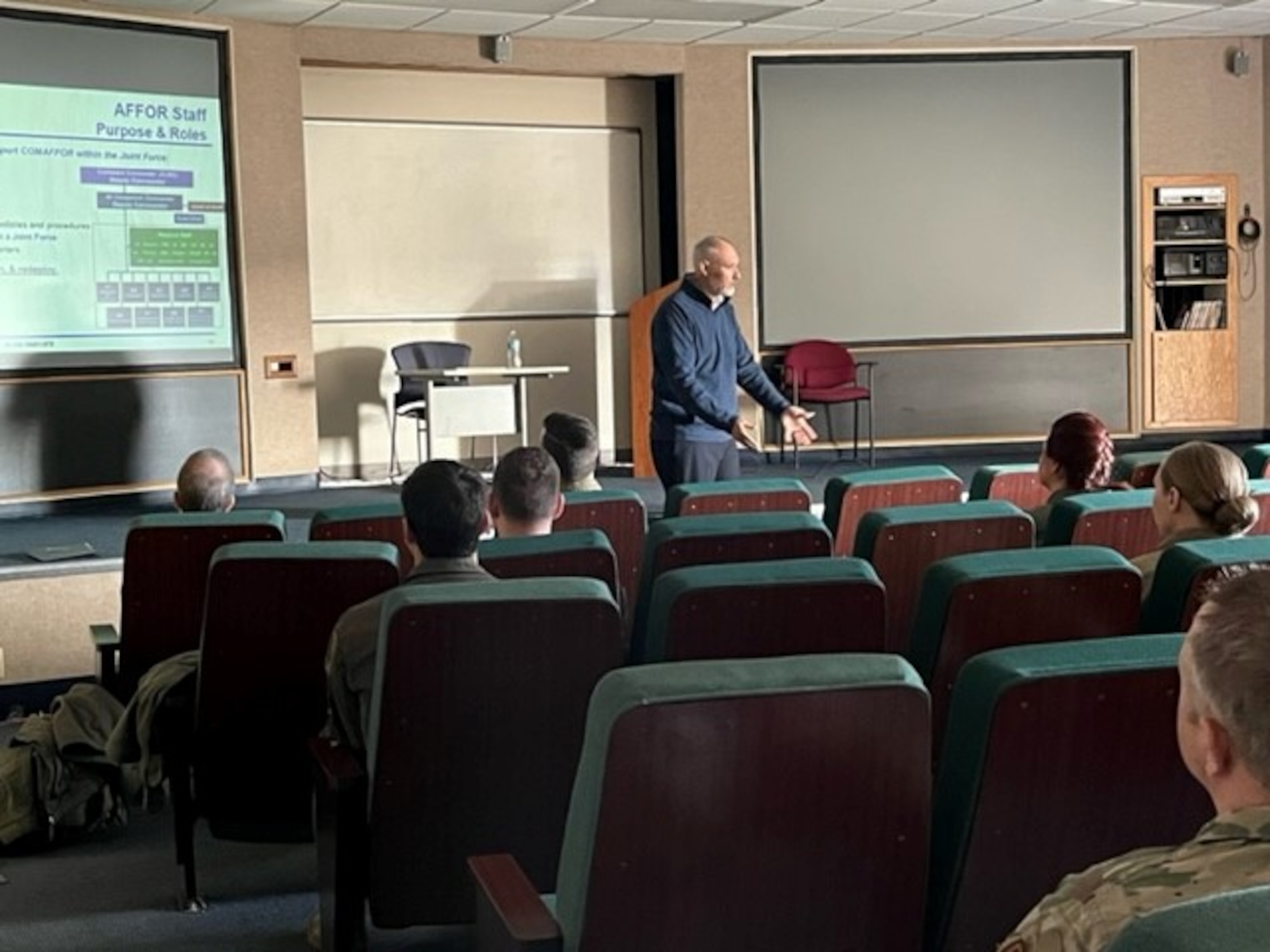 Photo of USAF Airman standing in front of screen teaching classroom of USAF Airmen