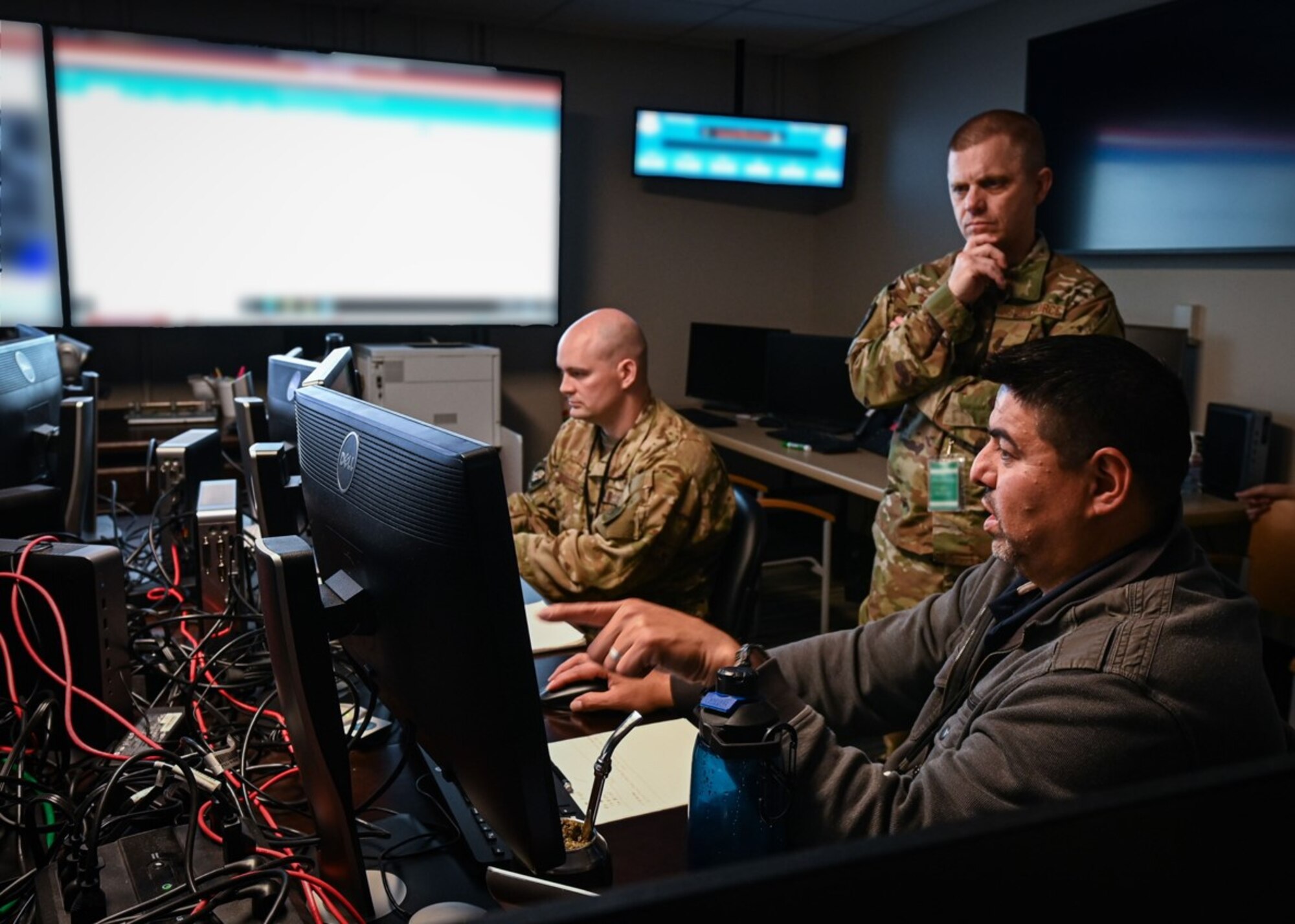 U.S. Air Force Lt. Col. Trevor Millette, Ninth Air Force (Air Forces Central) Exercise Crisis Action Team director, left, Master Sgt. Joshua Marcum, center, and Robert Frisina, Ninth Air Force (Air Forces Central) Exercise Crisis Action Team operations officers, discuss the on-going Air and Missile Defense Exercise at Shaw Air Force Base, South Carolina on May 11, 2022. AMDEX is a semi-annual exercise that develops and fortifies procedures against simulated air and missile threats in addition to strengthening dispersed operations capabilities. (U.S. Air Force photo by Staff Sgt. Draeke Layman)