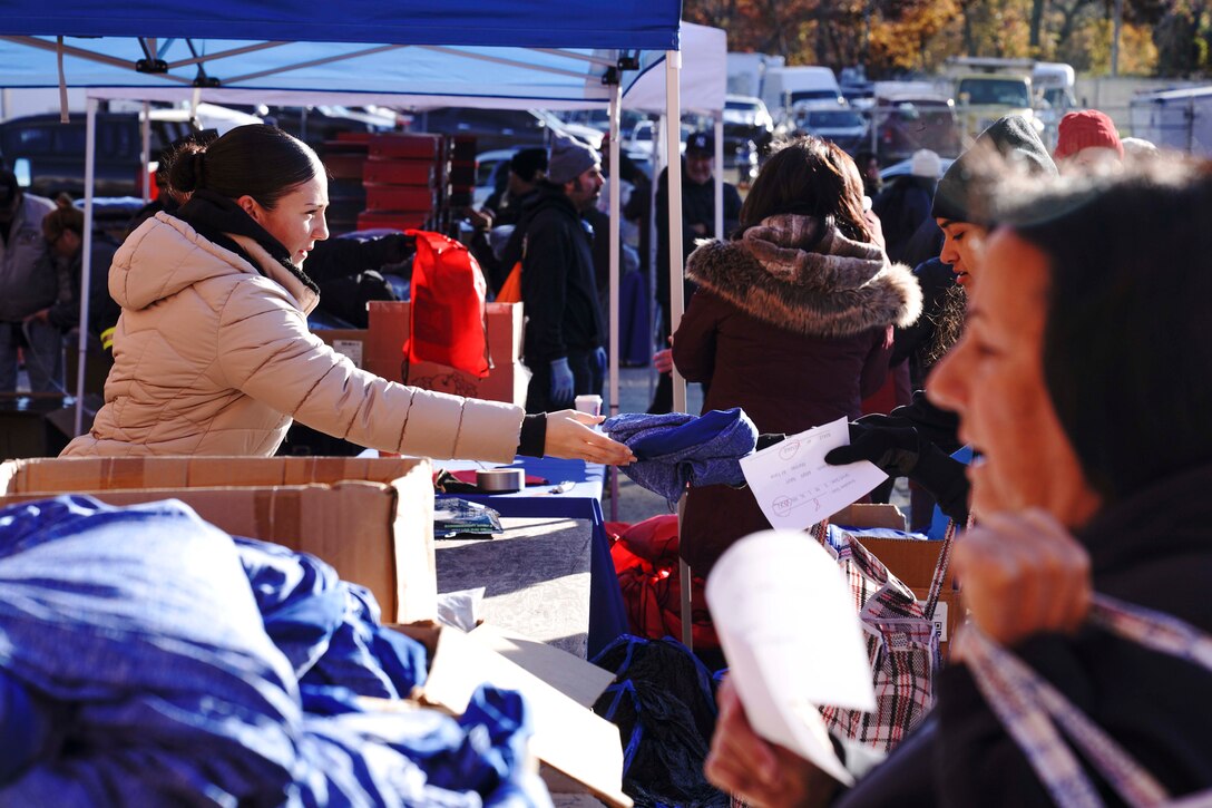 Sgt. Nikki J. Hunter, left, a Logistics clerk with 1st Marine Corps District, helps distribute clothing to veterans during the Veterans Stand Down, Nov. 23, 2021, at New York State Armory, Freeport, NY. The semi-annual Long Island Veterans Stand Down brings together different tri-state organizations including American Legion, General Needs, and Long Island Cares, among others, to assist with food, clothing, lodging assistance, and generating veteran suicide awareness to help veterans in need. (U.S. Marine Corps photo by Sgt. Tojyea G. Matally)