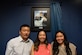 A man and two women pose in front of a photo of U.S. Staff Sgt. Franklin Kaunang