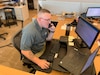 Man works on computer while making a phone call.