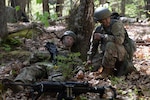 From left, Officer Candidate Bryce Murdick of the New Hampshire Army National Guard plays a battlefield casualty while Officer Candidate Rachel Gomes of the Rhode Island Army National Guard assesses his injuries and calls for a litter during the Region 1 Officer Candidate School Field Leadership Exercise on May 14, 2022, in Center Strafford, N.H.