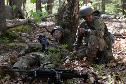 From left, Officer Candidate Bryce Murdick of the New Hampshire Army National Guard plays a battlefield casualty while Officer Candidate Rachel Gomes of the Rhode Island Army National Guard assesses his injuries and calls for a litter during the Region 1 Officer Candidate School Field Leadership Exercise on May 14, 2022, in Center Strafford, N.H.