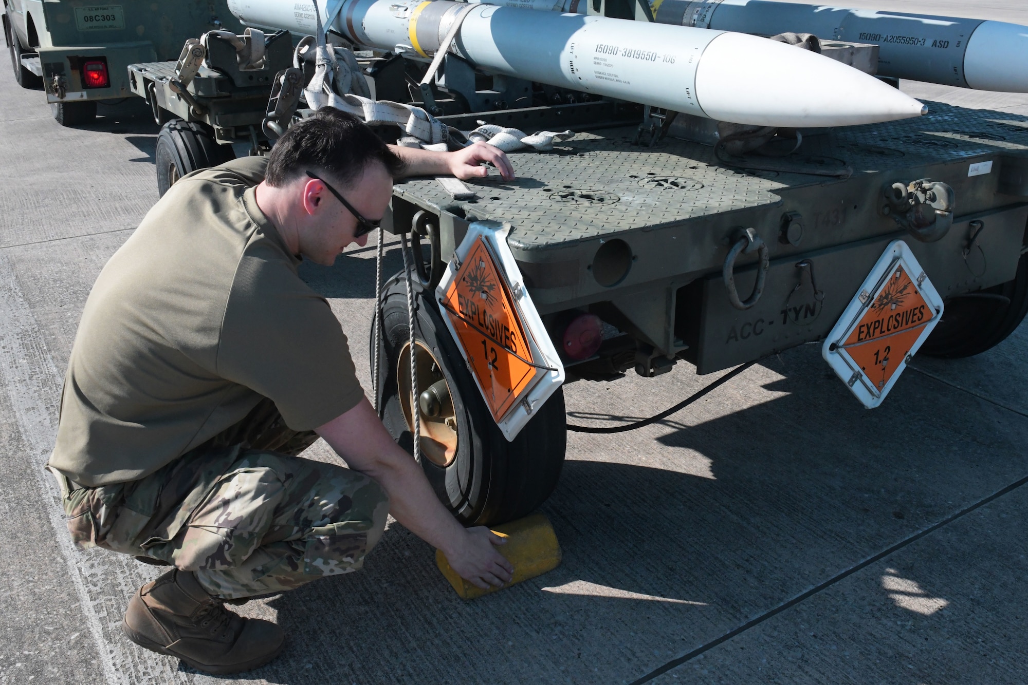 U.S. Air Force Senior Airman Cory Limbaugh, 325th Munitions Squadron crew chief, places a chock around the tires of a munitions handling trailer at Tyndall Air Force Base, Florida, May 10, 2022.