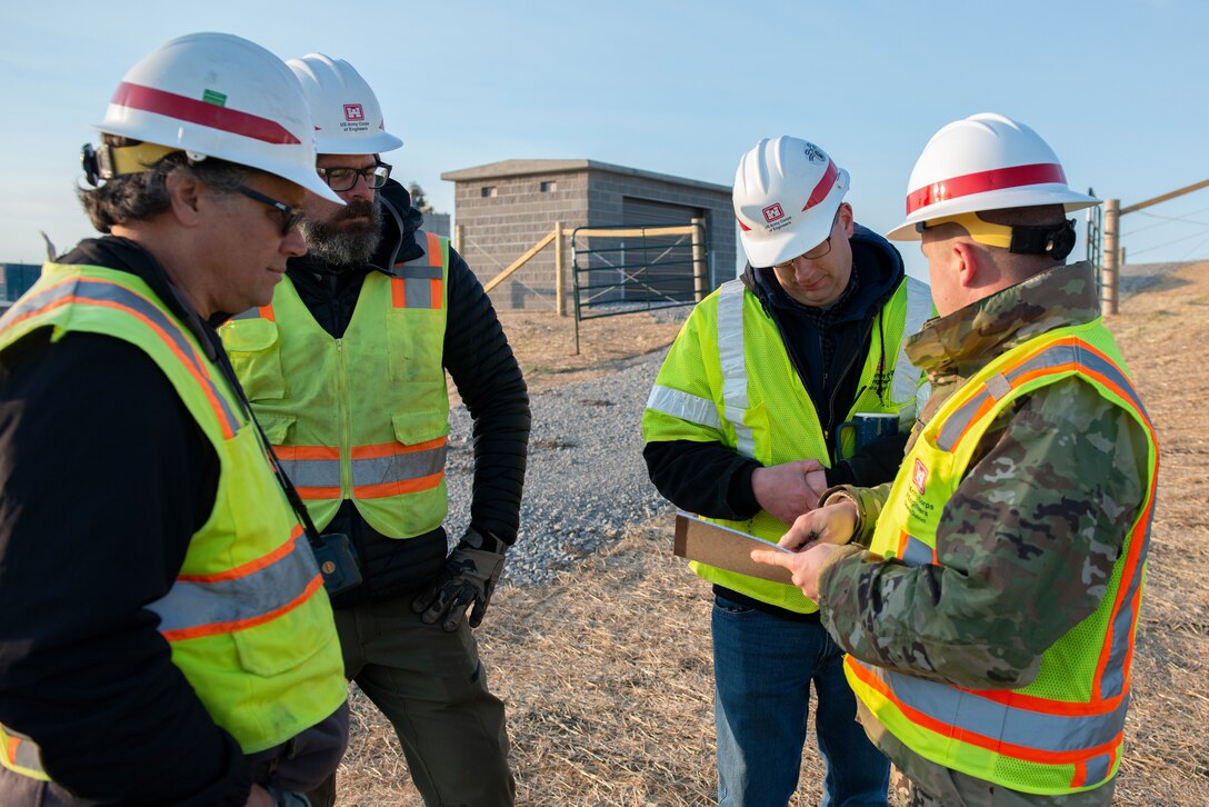 US Army Corps of Engineers, Omaha District members converse after inspecting the installation of flood gate panels along the highway leading to Hamburg Iowa, 24 Apr., 2022.
