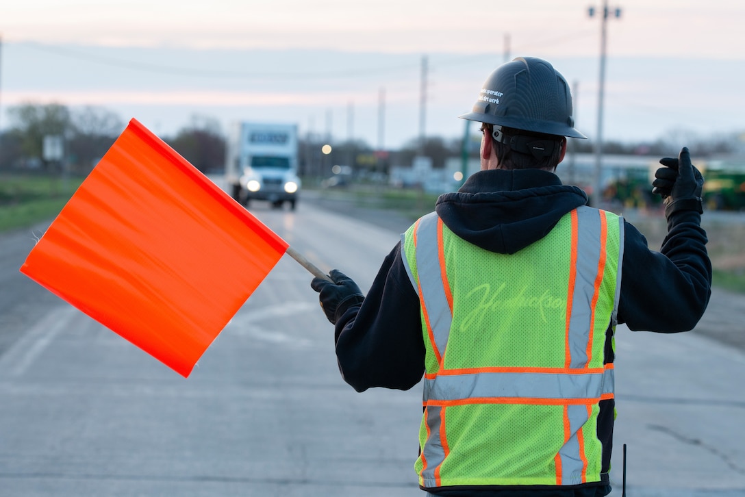 Traffic is directed through during the installation of flood gate panels along the highway leading to Hamburg Iowa, 24 Apr., 2022.