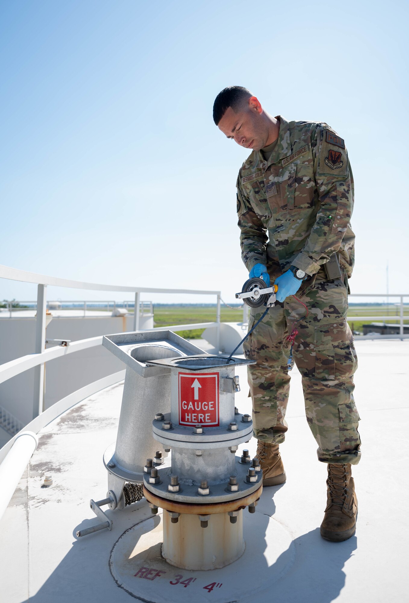 An Airman drops a measuring tool into a fuel tank.