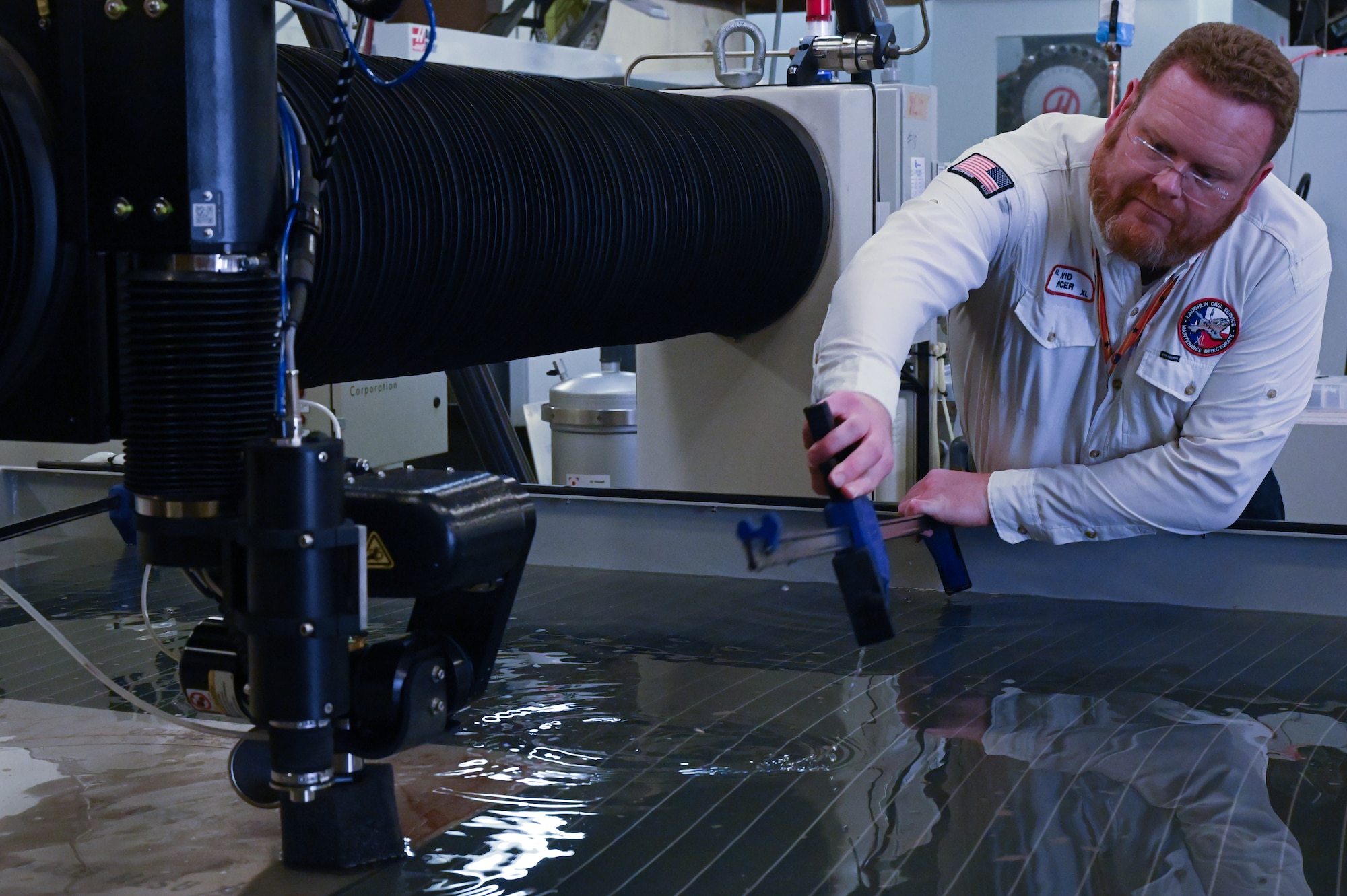 David Mercer, 47th Flying Training Wing fabrication supervisor, removes the extension utility handle at Laughlin Air Force Base, Texas, on April 26, 2022. The water jet ensures no heat-affected zones or mechanical stress on the material. (U.S. Air Force photo by Airman 1st Class Keira Rossman)