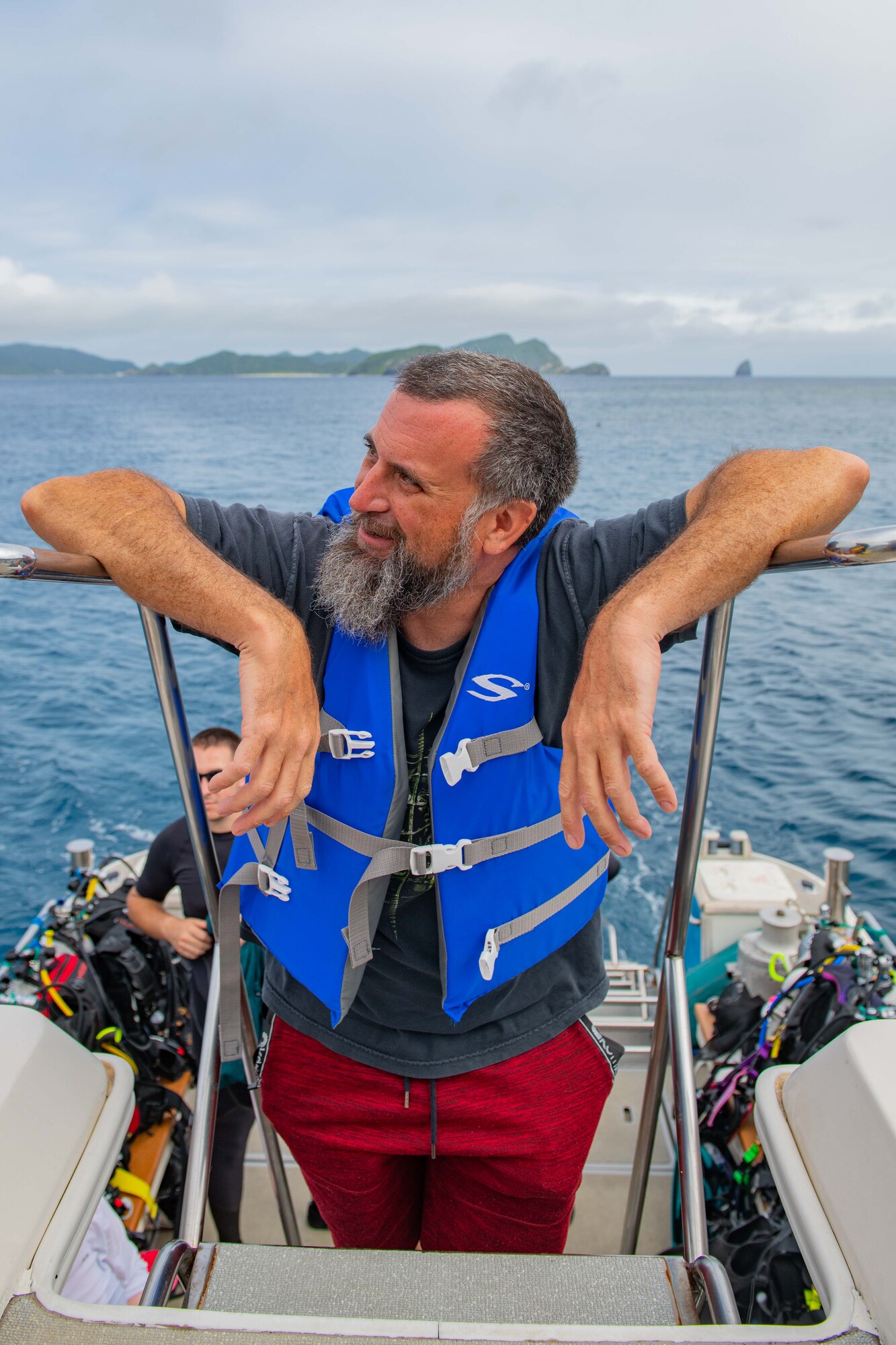 A scuba diver enjoys the scenery from the top deck of a boat