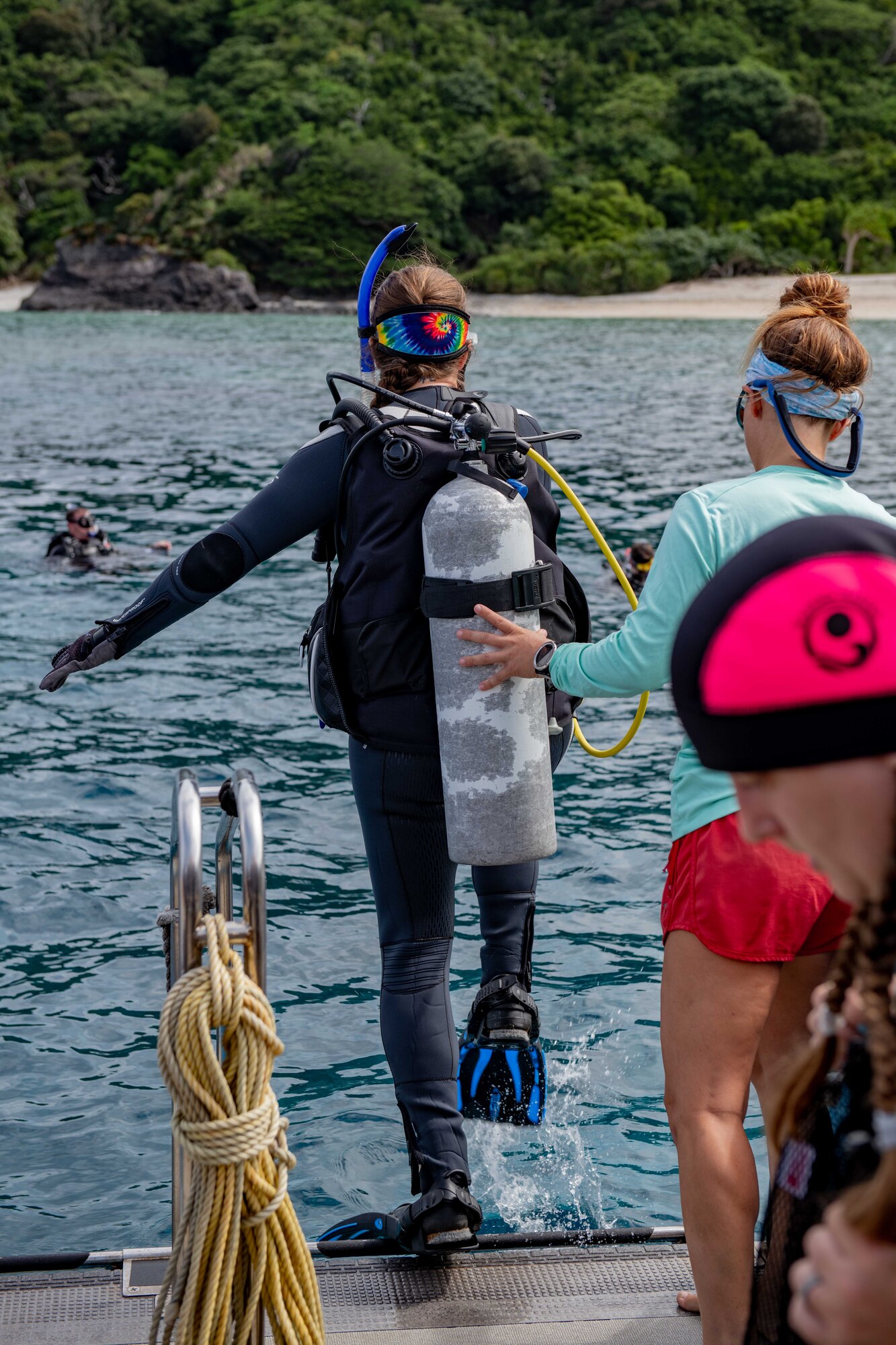 A scuba diver gets helped into the ocean by the ships deckhand