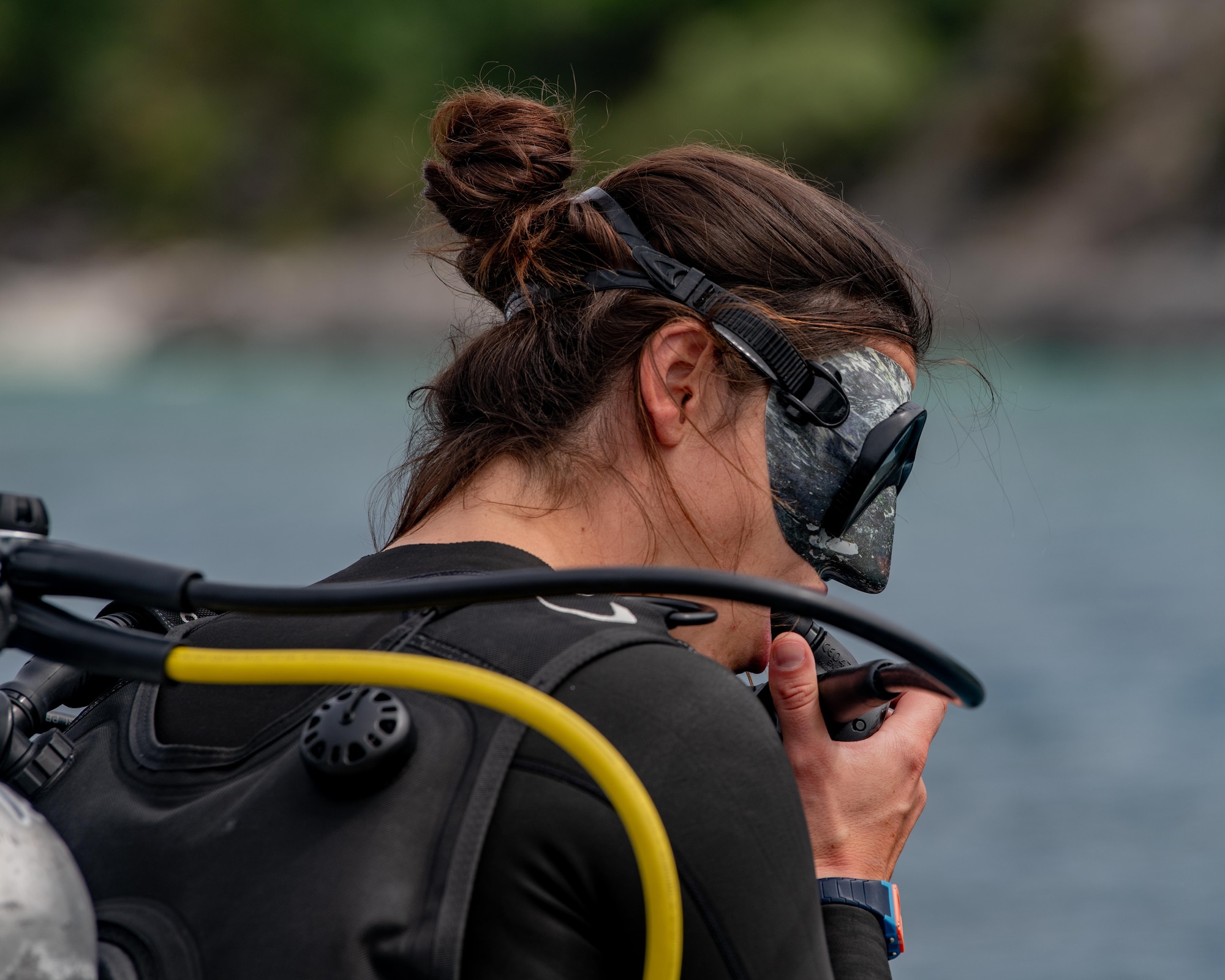 A female diver places a mouthpiece into her mouth