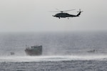 220516-N-TT059-1005 GULF OF OMAN (May 16, 2022) An MH-60R Seahawk from Helicopter Maritime Strike Squadron (HSM) 35, Detachment 1, provides aerial support to an interdiction team from guided-missile destroyer USS Momsen (DDG 92) approaching a fishing vessel May 16. The vessel was seized while transiting international waters in the Gulf of Oman.