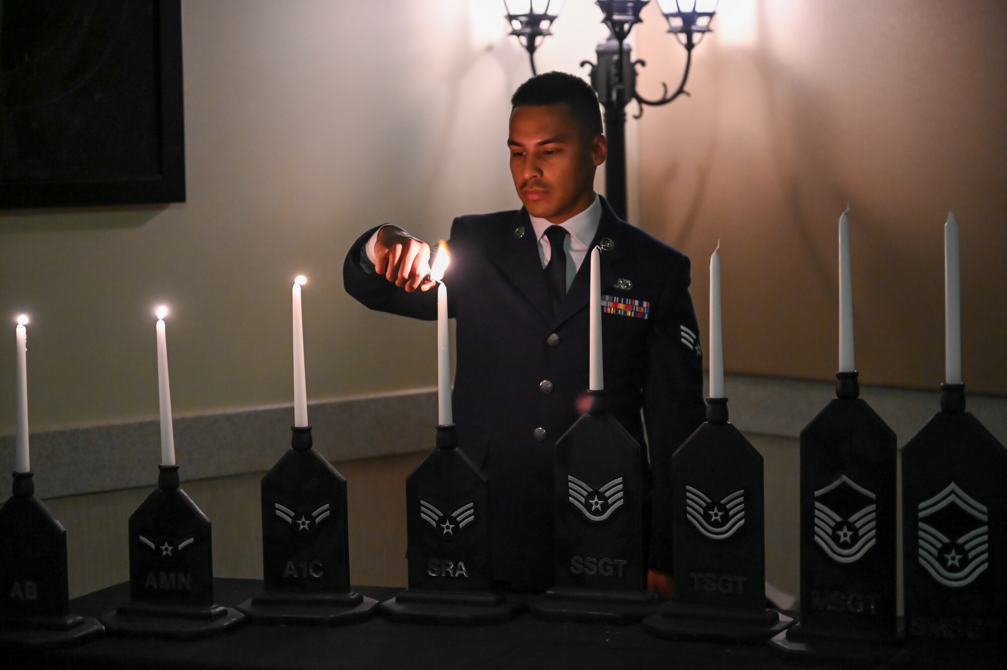 Senior Airman Sergio Landin, 75th Logistics Readiness Squadron, lights the candle representing the rank of senior airman during Hill Air Force Base's Chief Induction Ceremony