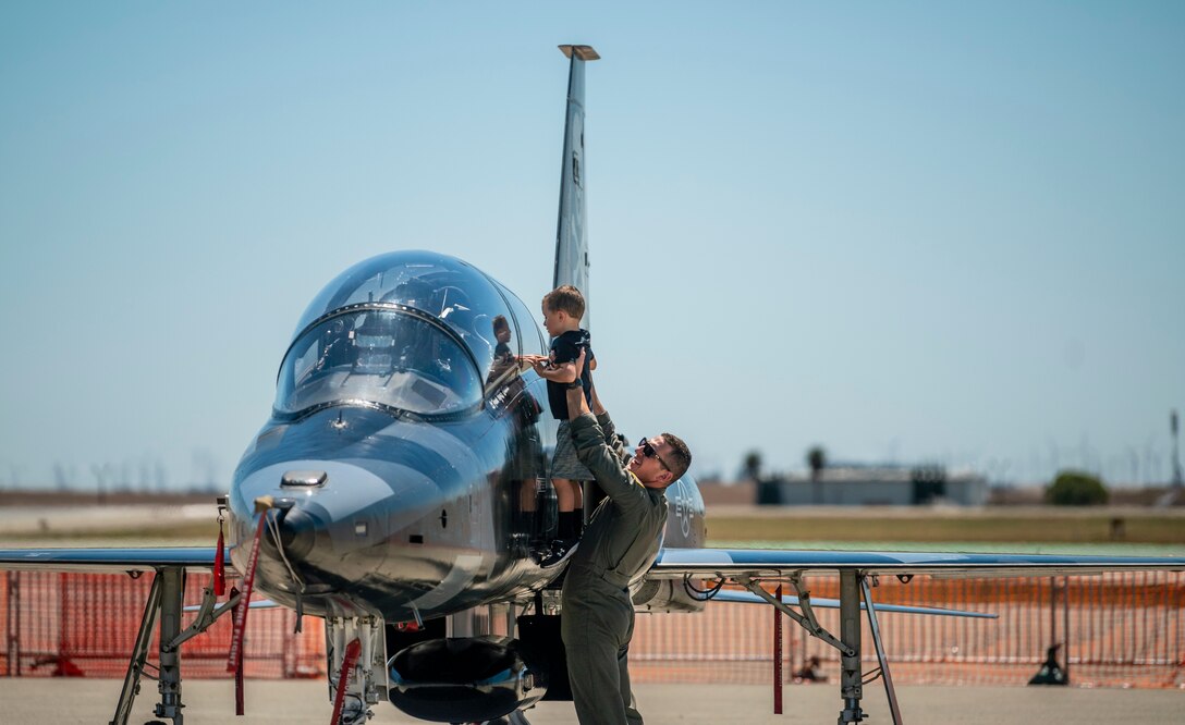 First Lt. Ryan Durgarian, 70th Air Refueling Squadron KC-10 Extender pilot, raises his son Luke, to get a better view of a T-38C during the Wings Over Solano open house and air show rehearsal at Travis Air Force Base, Calif., May 13, 2022. The air show rehearsal provided an opportunity for Department of Defense employees and their families to see the installation’s full capabilities. (U.S. Air Force photo by Senior Airman Karla Parra)