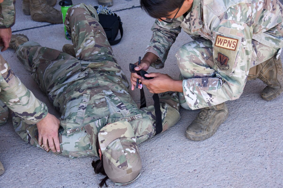 A photo of Airmen performing Tactical Combat Casualty Care on a simulated injury.