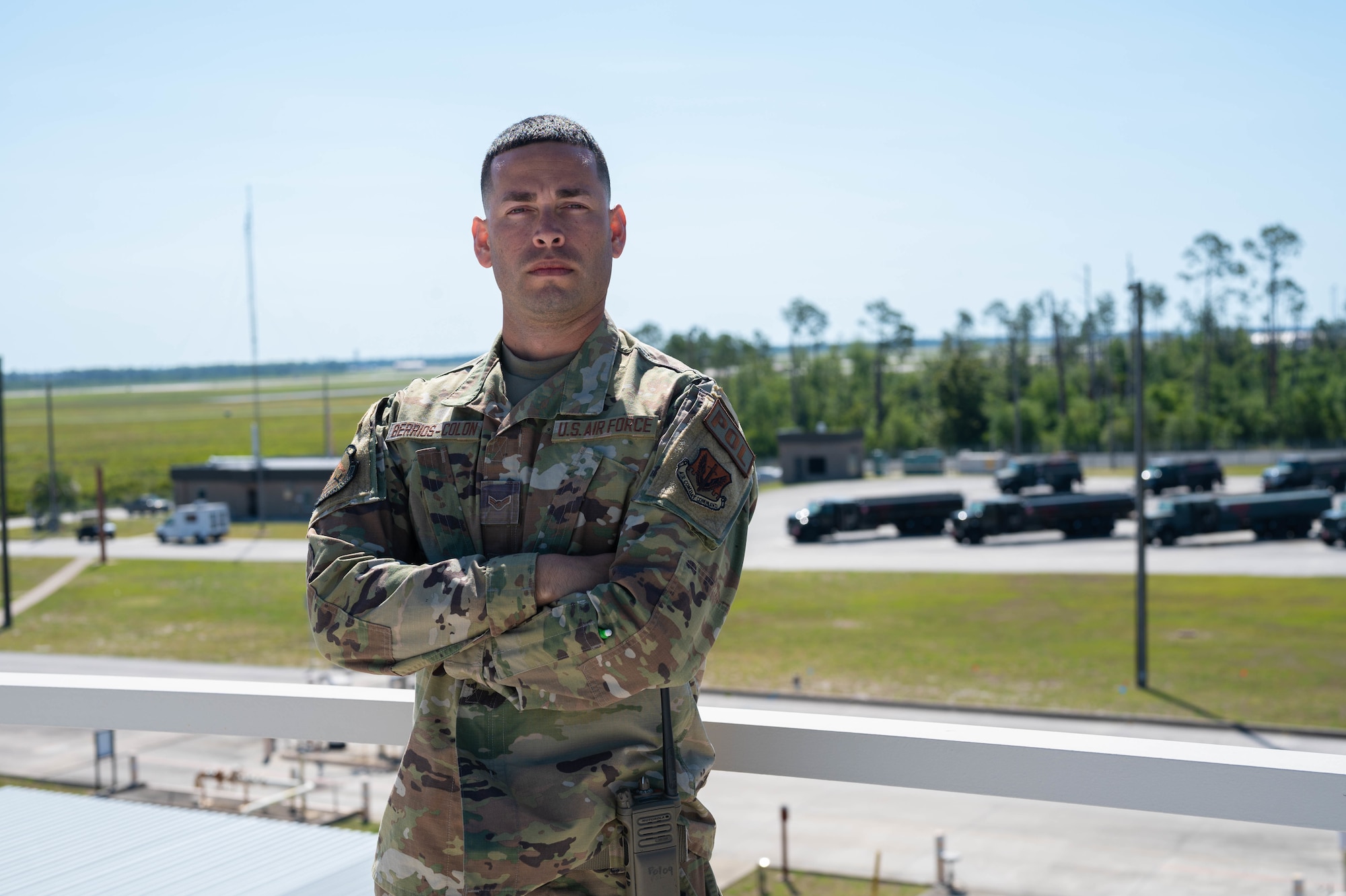 An Airman poses for a photo in front of fuel trucks.