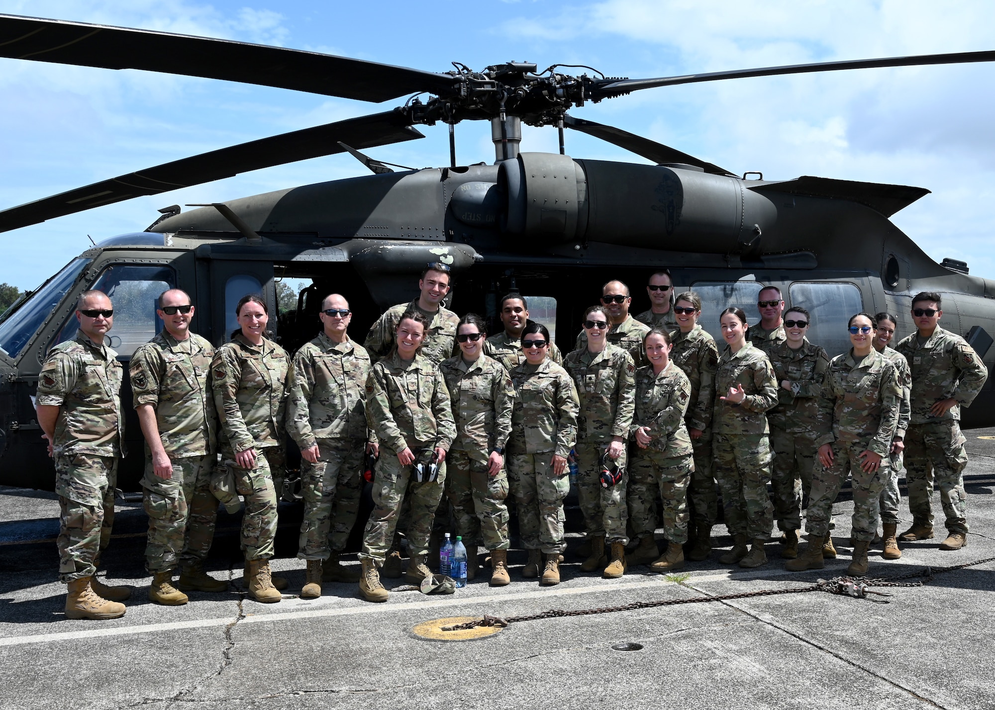 Members from the 104th Medical Group stand in front of an Army UH-60 Black Hawk helicopter before a morale flight at Wheeler Army Airfield, Hawaii, May 3, 2022. Airmen are in Hawaii to complete training requirements at Tripler Army Medical Center. (U.S. Air National Guard Photo by Senior Airman Camille Lienau)