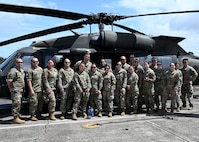 Members from the 104th Medical Group stand in front of an Army UH-60 Black Hawk helicopter before a morale flight at Wheeler Army Airfield, Hawaii, May 3, 2022. Airmen are in Hawaii to complete training requirements at Tripler Army Medical Center. (U.S. Air National Guard Photo by Senior Airman Camille Lienau)