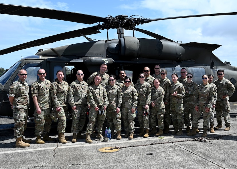 Members from the 104th Medical Group stand in front of an Army UH-60 Black Hawk helicopter before a morale flight at Wheeler Army Airfield, Hawaii, May 3, 2022. Airmen are in Hawaii to complete training requirements at Tripler Army Medical Center. (U.S. Air National Guard Photo by Senior Airman Camille Lienau)