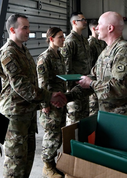 Tech. Sgt. Jason Gillete, 104th Fighter Wing communications technician, shakes the hand of U.S. Army Lt. Col. Patrick Donnelly, Task Force Powderhorn senior leader, during the TF Powderhorn awards ceremony at Barnes Air National Guard Base, Massachusetts, May 14, 2022. Fifty four Barnestormers were awarded Army Achievement Medals for their outstanding performance during TF Powderhorn, an activation where members supported state medical facilities. (U.S. Air National Guard Photo by Senior Airman Camille Lienau)
