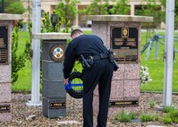 DSCC Police chief in uniform laying a wreath at a memorial in front of Building 58.