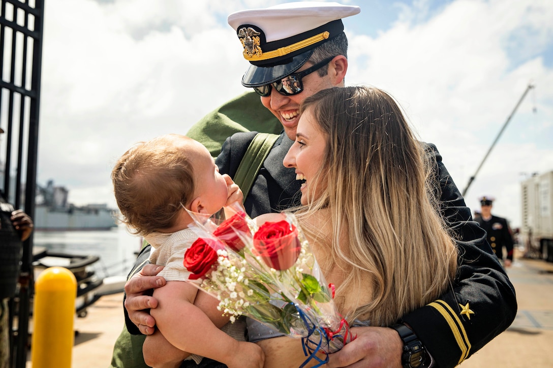 A sailors hugs his wife and son.