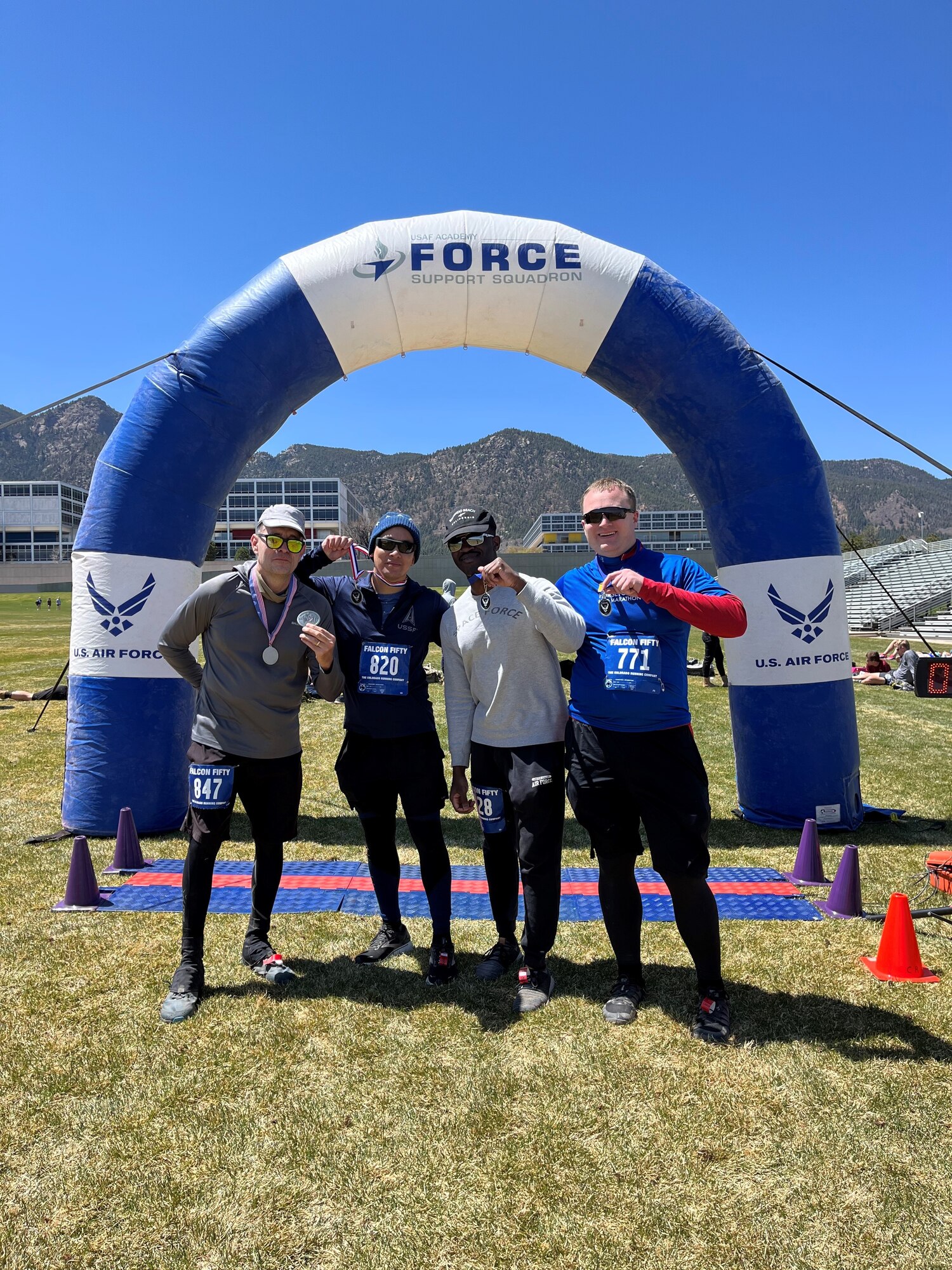 Four people stand at race finish line