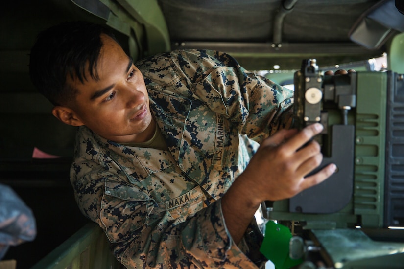 A man in uniform is looking at and adjusting a piece of equipment.