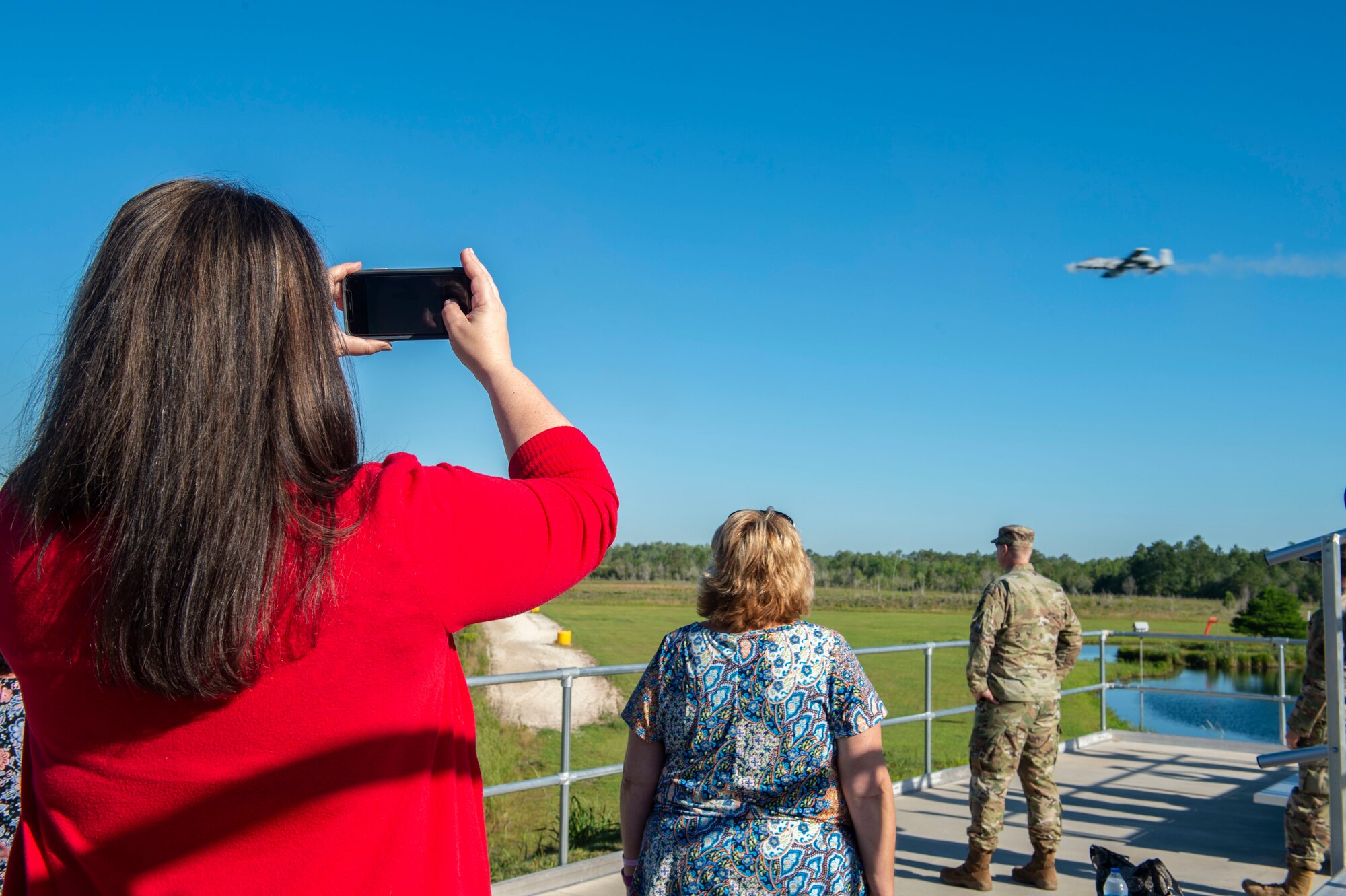 woman taking picture of A-10 flying