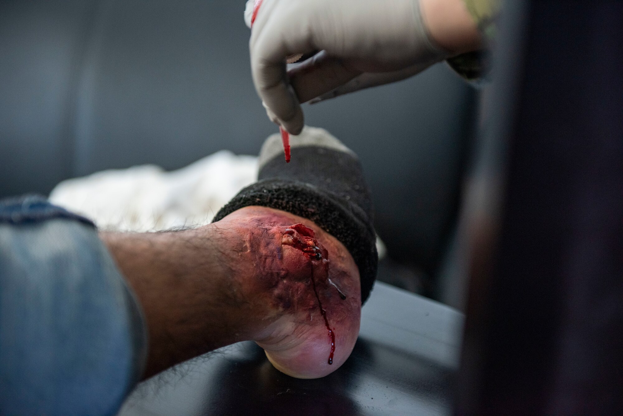 A Navy sailor applies simulated blood to a mock wound