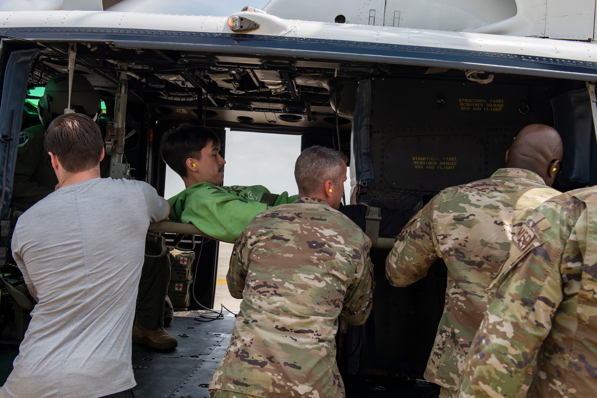 Airmen secure a mock patient into a helicopter