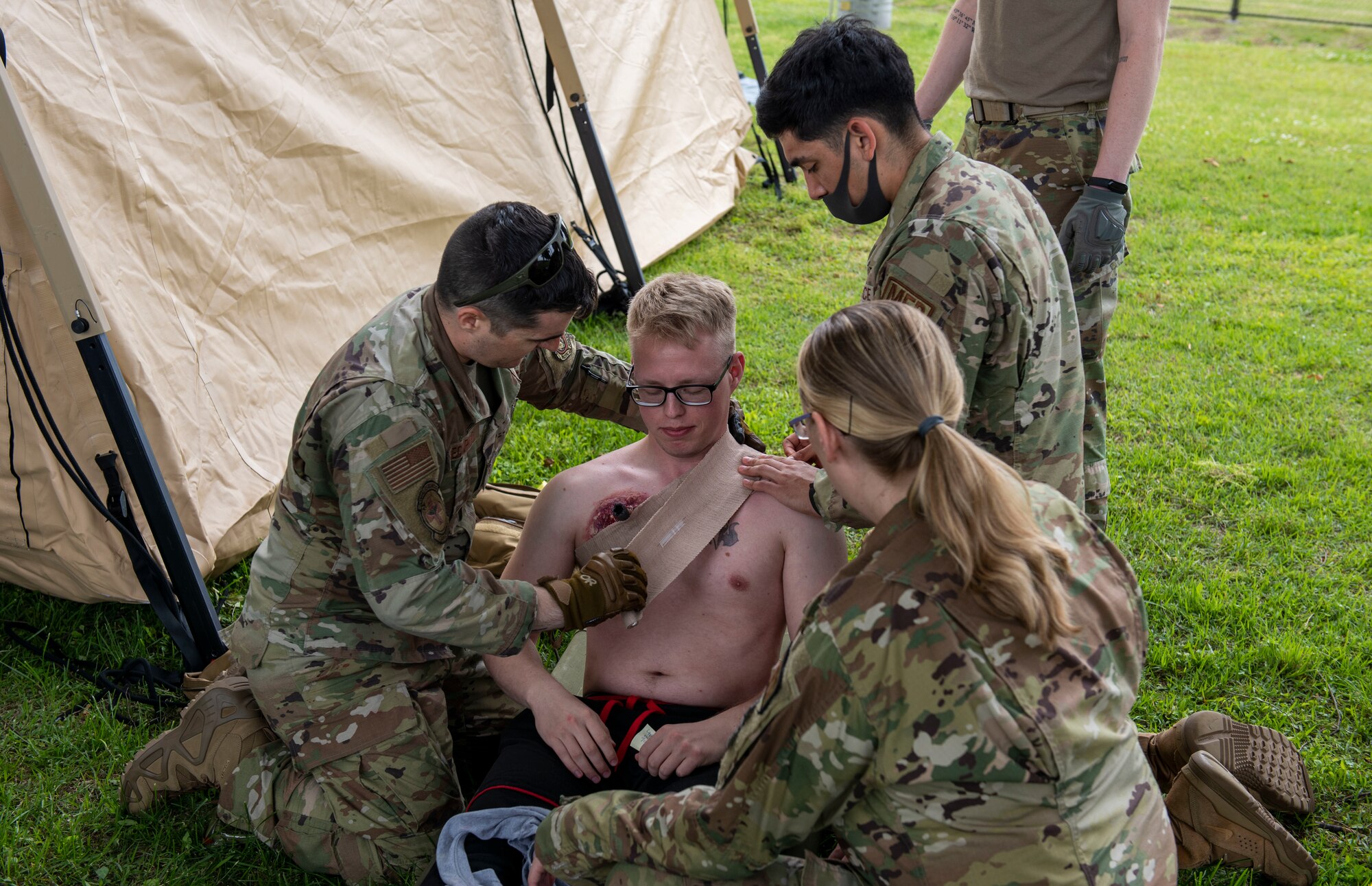 Personnel from the 374th Medical Group wrap a bandage on a fake wound