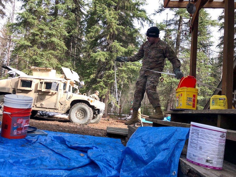 Alaska Army Guard Sgt. Fabrain Alexander, the task force noncommissioned officer in charge and a military policeman with the 297th Military Police Company, sets up a water vacuum suction hose while assisting with cleanup and flood recovery efforts in Manley Hot Springs May 12-15, 2022. The State Emergency Operations Center requested the AKNG for support following a state disaster declaration on May 7 for the Yukon Koyukuk Regional Education Attendance Area.